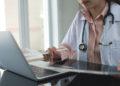 Female doctor working on laptop computer searching the information and using digital tablet at doctor's office. Medical student using computer, healthcare and medicine concept